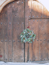 Corona de Navidad con frutos rojos y piñas