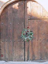 Corona de Navidad con frutos rojos y piñas