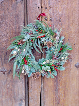 Corona de Navidad con frutos rojos y piñas