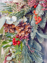 Corona de Navidad con frutos rojos y piñas