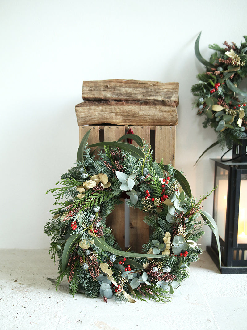 Corona de Navidad con frutos rojos y piñas